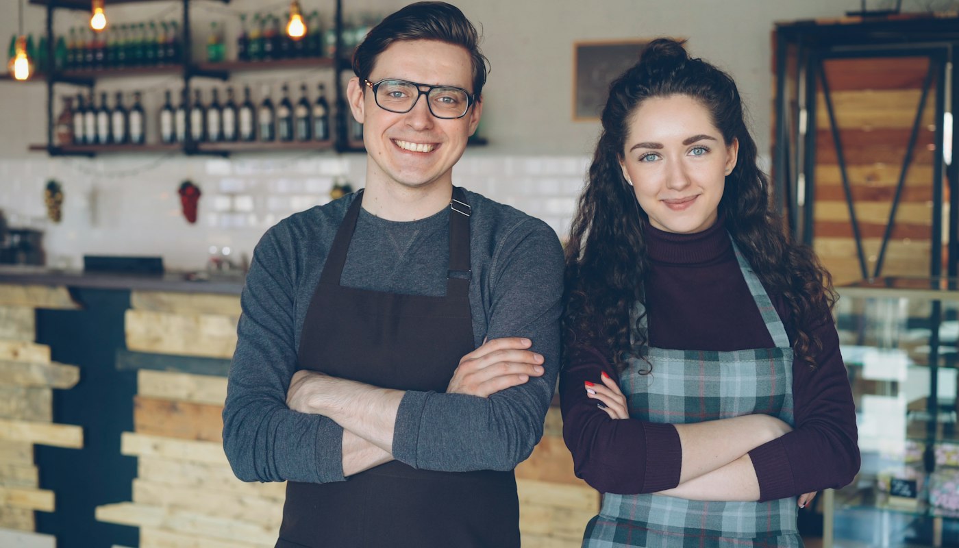 Two smiling small business owners in their cafe